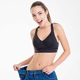 Happy female model showing slimmer waist by showing oversized pants